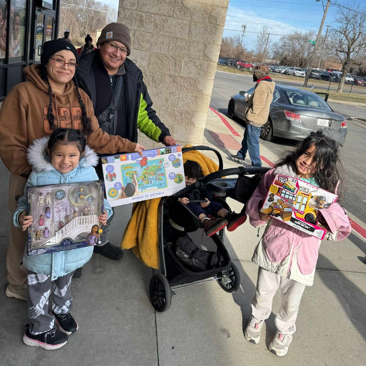 A family with young children holding toys at a community giveaway