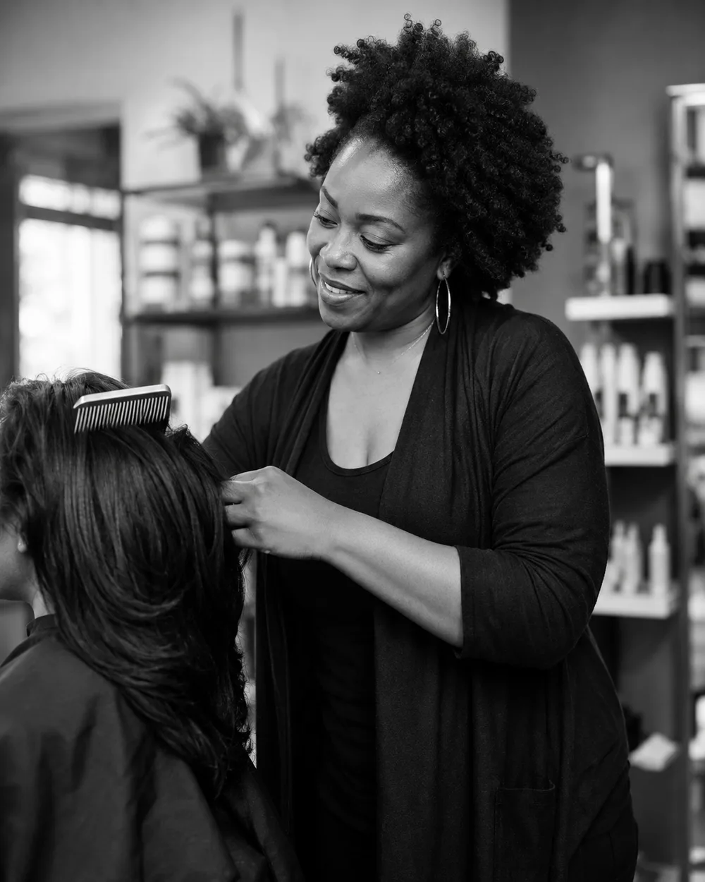A professional stylist combing a client&rsquo;s hair in a salon